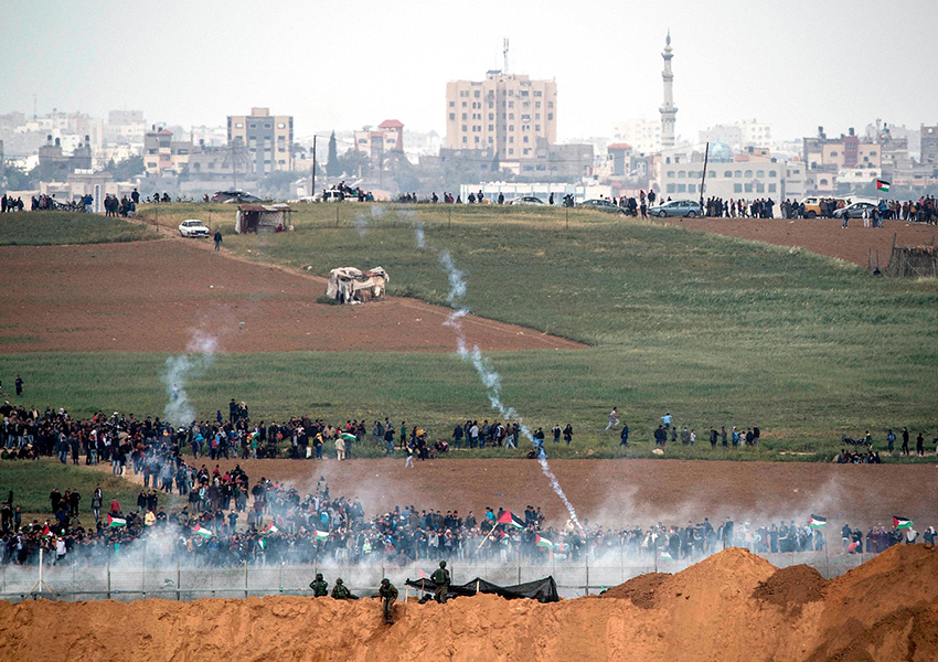 Tentara Israel menembakkan gas air mata ke arah demonstran Palestina di dekat pagar perbatasan pada bulan Maret. (Foto: Associated Press/Tsafrir Abayov)