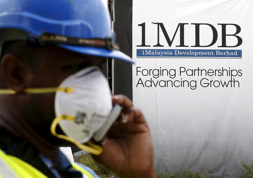Seorang pekerja konstruksi berbicara di telepon di depan papan iklan 1Malaysia Development Berhad (1MDB) di pembangunan Tun Razak Exchange di Kuala Lumpur, Malaysia, 3 Februari 2016. (Foto: REUTERS/Olivia Harris/File Photo)