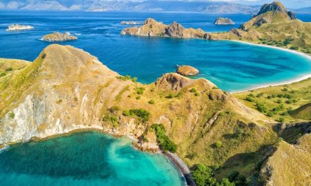 Pemandangan udara dari dua teluk berwarna biru kehijauan di pulau Pulau Padar, di antara Pulau Komodo dan Rinca di dekat Labuan Bajo di Indonesia. Shutterstock