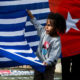 Seorang anak laki-laki membantu membentangkan bendera nasionalis Papua Barat, yang dikenal sebagai Bintang Kejora