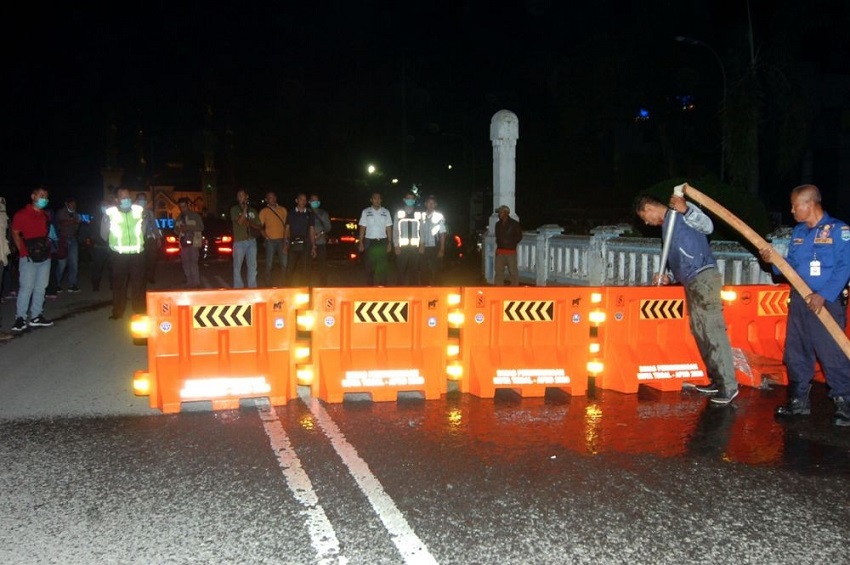 Petugas melakukan pengalihan jalur saat penutupan sebagian jalan protokol di Kota Tegal, Jawa Tengah, Senin malam, 22 Maret 2020. Pemkot dan Polres Tegal hingga 14 hari mendatang menerapkan local lockdown dengan menutup jalur Pantura yang melintasi kota, akses masuk alun-alun, dan mematikan sebagian lampu jalan protokol untuk membatasi kendaraan yang akan masuk ke kota dan mencegah kerumunan massa di jalanan.
