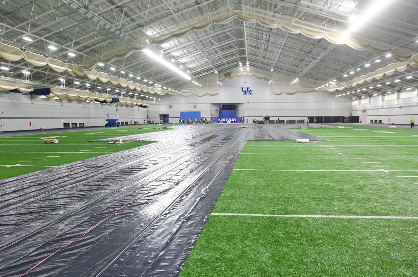 Para pekerja melapisi lapangan rumput di fasilitas latihan sepak bola tim University of Kentucky, Nutter Field House saat dipersiapkan sebagai lokasi rumah sakit darurat COVID-19 di Kota Lexington,negara bagian Kentucky, Amerika Serikat, 4 April 2020. 